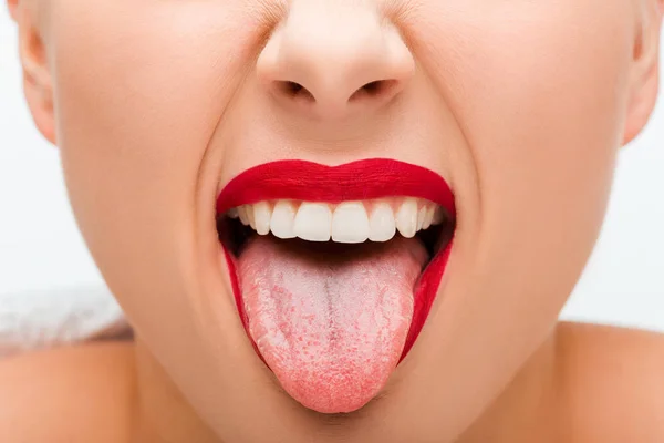 Vista recortada de mujer joven con lápiz labial rojo que sobresale lengua aislada en blanco - foto de stock