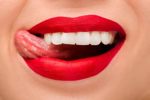 Обрізаний вид веселої жінки з червоною помадою, що стирчить язиком ізольовано на білому — стокове фото