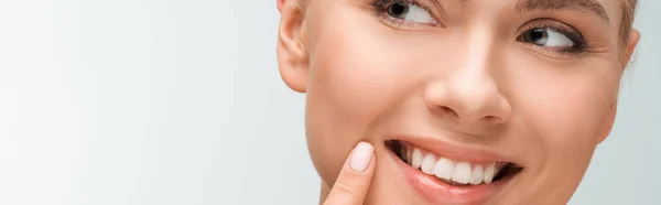 Plano panorámico de mujer feliz señalando con el dedo en la cara aislado en blanco - foto de stock