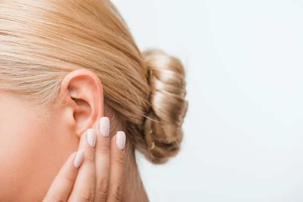 Vista recortada de mujer rubia tocando oreja aislada en blanco - foto de stock