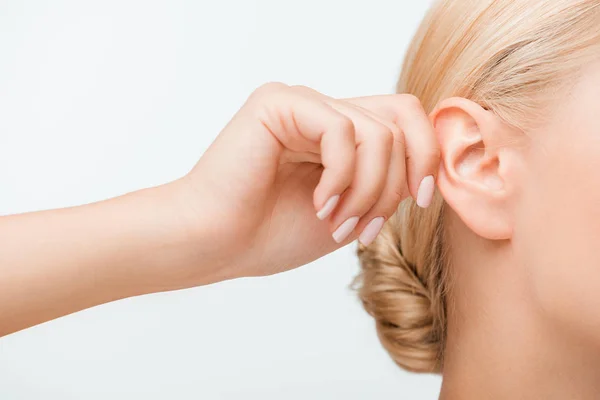 Corte vista de loira menina tocando orelha enquanto escuta isolado no branco — Fotografia de Stock