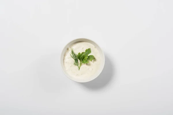 Top view of tasty tzatziki sauce with greenery on white background — Stock Photo