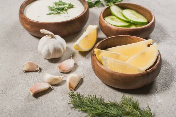 Selective focus of lemon, cucumber with garlic and tzatziki sauce on stone surface — Stock Photo