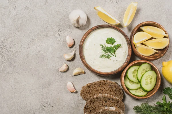 Top view of tzatziki sauce with bread and organic ingredients on stone background — Stock Photo