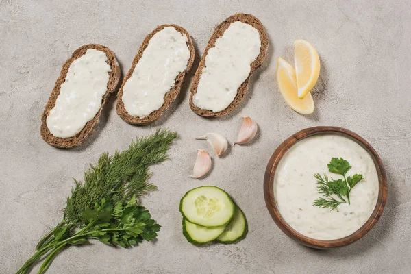 Top view of bread with tzatziki sauce and ingredients on stone background — Stock Photo