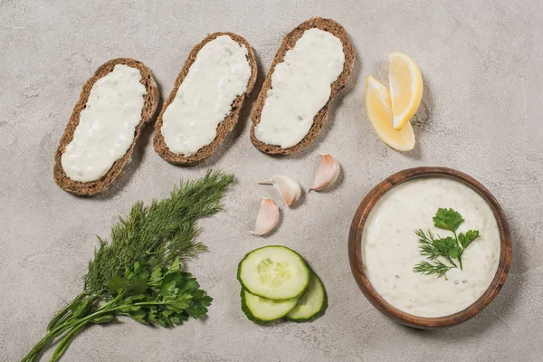 Vista dall'alto del pane con salsa tzatziki e ingredienti su sfondo di pietra — Foto stock