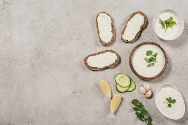 Top view of homemade tzatziki sauce with bread and ingredients on stone background — Stock Photo