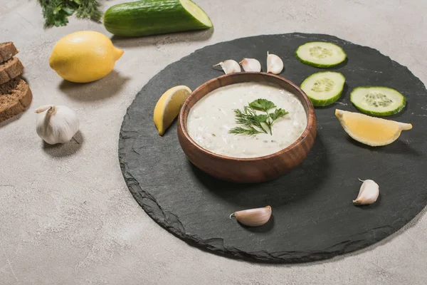 Gourmet tzatziki sauce with raw ingredients on stone surface — Stock Photo