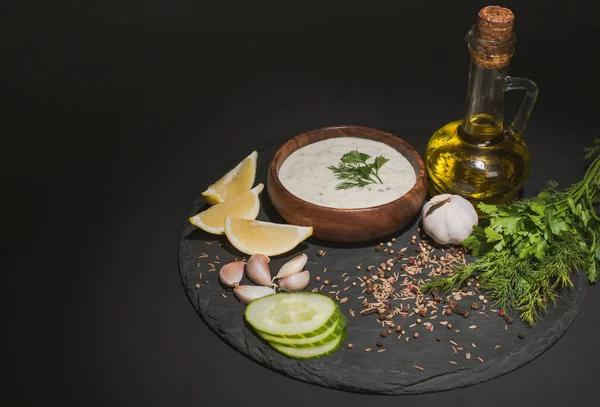 Tzatziki соус с органическими ингредиентами, специями и оливковым маслом на темном фоне — стоковое фото