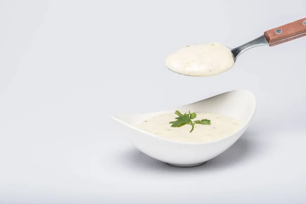 Salsa tzatziki casera con cuchara sobre fondo blanco - foto de stock