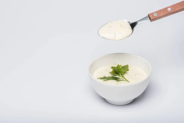 Molho tzatziki saboroso com vegetação e colher no fundo branco — Fotografia de Stock