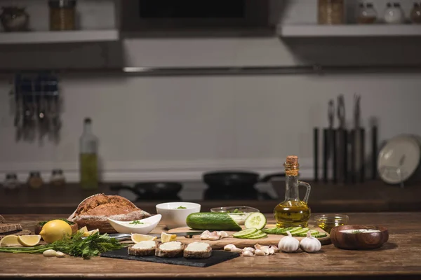 Fresh ingredients for tzatziki sauce on cutting board on kitchen table — Stock Photo