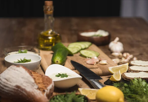 Salsa Tzatziki con pan y verduras crudas en la mesa de la cocina - foto de stock
