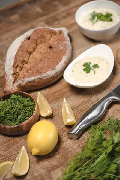 Homemade tzatziki sauce with bread and raw ingredients on wooden table — Stock Photo