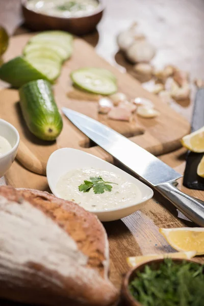 Focus selettivo della salsa tzatziki con pane e verdure sul tavolo di legno — Foto stock