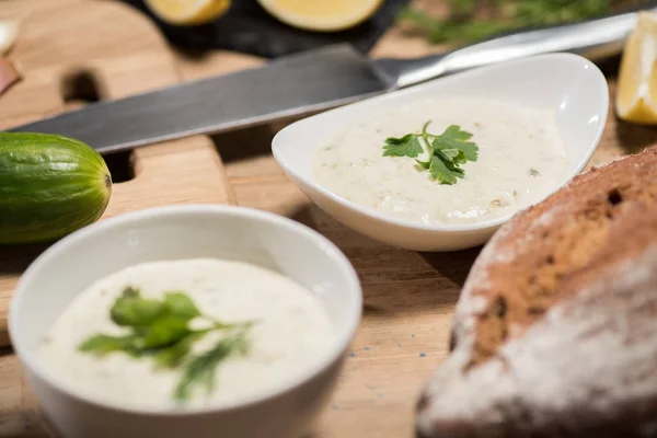 Selective focus of bowls with tzatziki sauce with bread on wooden table — Stock Photo