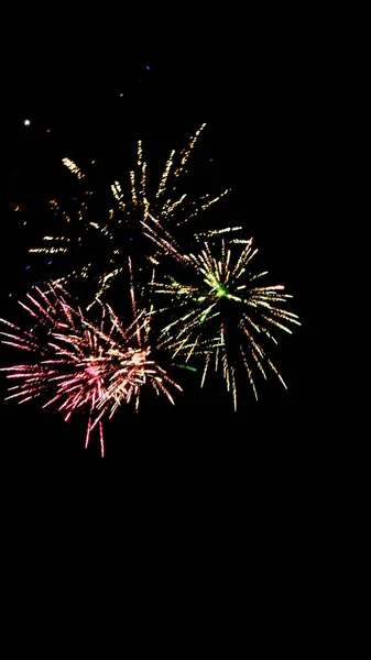 Fuegos artificiales tradicionales coloridos en el cielo oscuro de la noche, aislados en negro - foto de stock