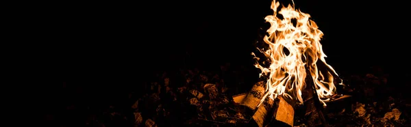 Panoramic shot of flame and logs in camp fire in darkness in the night — Stock Photo