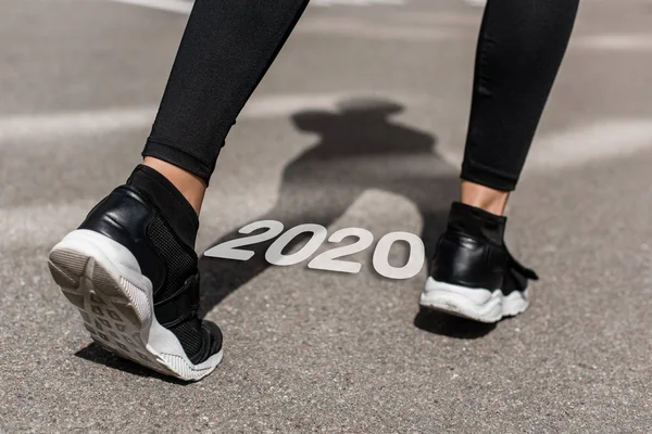 Cropped view of sportswoman on running track near 2020 lettering — Stock Photo