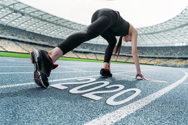 Jeune sportive debout dans commencer à positionner sur la piste de course près 2020 lettrage — Photo de stock