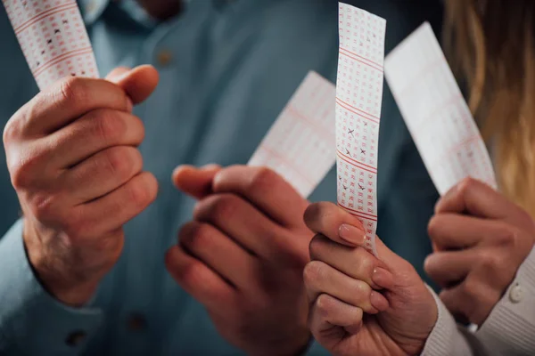 Cropped view of man and woman holding lottery tickets while waiting for lottery results — Stock Photo