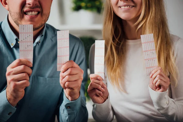 Cropped view of worried man and woman holding lottery tickets while waiting for lottery results — Stock Photo