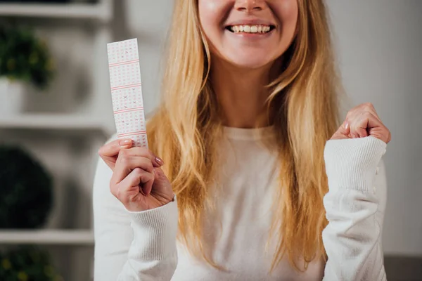 Ausgeschnittene Ansicht einer Frau, die beim Halten eines Lottoscheins Siegergeste zeigt — Stockfoto