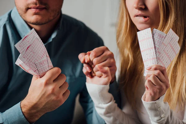 Ausgeschnittene Ansicht zweier besorgter Spieler, die Händchen halten, während sie auf Lottoergebnisse warten — Stockfoto