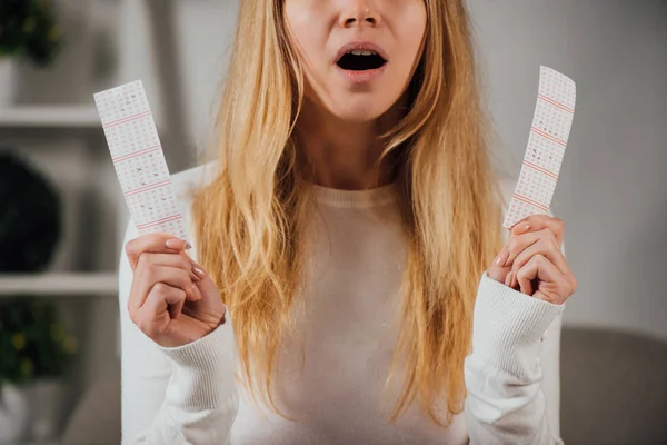 Vista recortada de la mujer sorprendida sosteniendo billetes de lotería - foto de stock