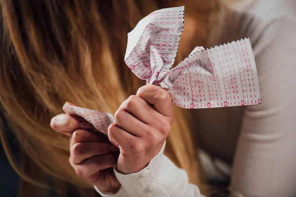 Foco seletivo de mulher chateada crumpling bilhete de loteria enquanto sentado com a cabeça curvada — Fotografia de Stock