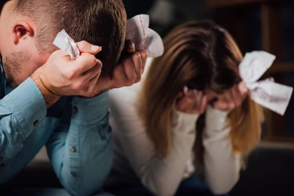 Selective focus of two upset gamblers sitting with bowed heads while holding crumpled lottery tickets — Stock Photo