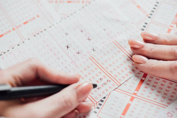Cropped view of woman marking numbers in lottery tickets — Stock Photo