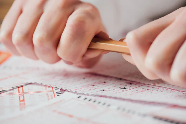 Ausgeschnittener Blick auf verärgerten Spieler, der Bleistift in der Nähe von Lottoscheinen bremst — Stockfoto