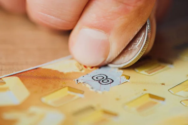 Nahaufnahme der Silbermünze in der Hand des Zockers, der Lottoschein zerkratzt — Stockfoto