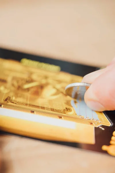 Selective focus of silver coin in hand of gambler scratching lottery ticket — Stock Photo