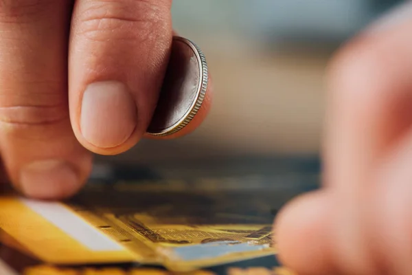 Vista de cerca de la moneda de plata en la mano del jugador cerca de billete de lotería rayado - foto de stock
