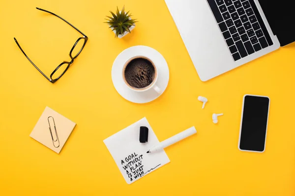 Paper napkin with goal without plan just wish inscription, felt-tip pen, laptop, smartphone, coffee cup, glasses, wireless headphones on yellow desk — Stock Photo