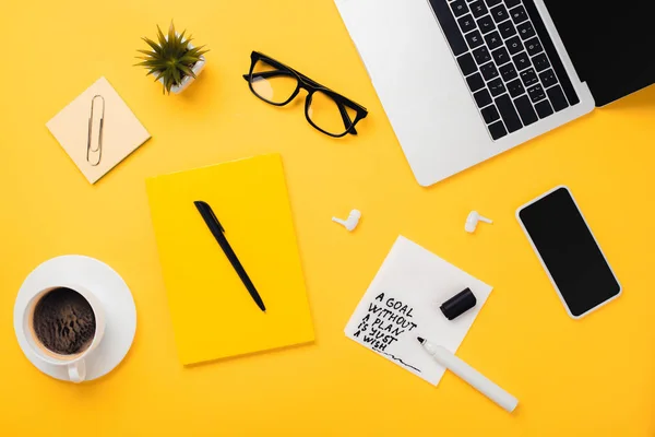 Papierserviette mit Ziel ohne Plan nur Wunschbeschriftung neben Kaffeetasse, Gläsern, Blumentopf, Digitalgeräten und Schreibwaren auf gelbem Schreibtisch — Stockfoto