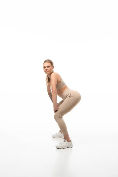 Side view of blonde girl in beige leggings twerking isolated on white — Stock Photo