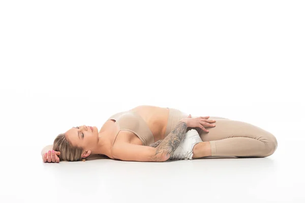Sexy twerk dancer in beige leggings lying on floor isolated on white — Stock Photo