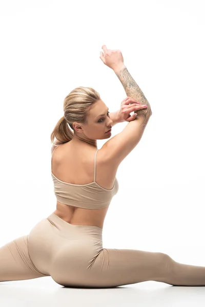 Blondes Mädchen in beigen Leggings macht Split, während sie isoliert auf Weiß twerkt — Stockfoto