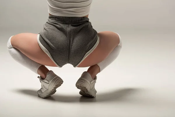 Partial view of young sexy girl in shorts twerking on white background — Stock Photo