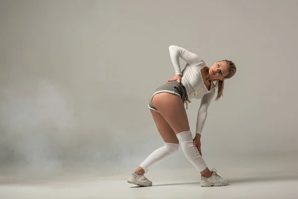 Jeune fille sexy en short twerking sur fond blanc avec de la fumée — Photo de stock