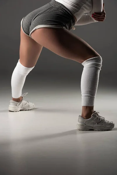 Partial view of young sexy girl in shorts twerking on grey background — Stock Photo