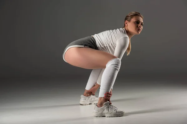 Side view of young sexy girl in shorts twerking on grey background — Stock Photo