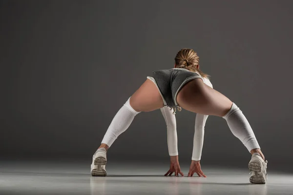 Back view of young sexy girl in shorts twerking on grey background — Stock Photo
