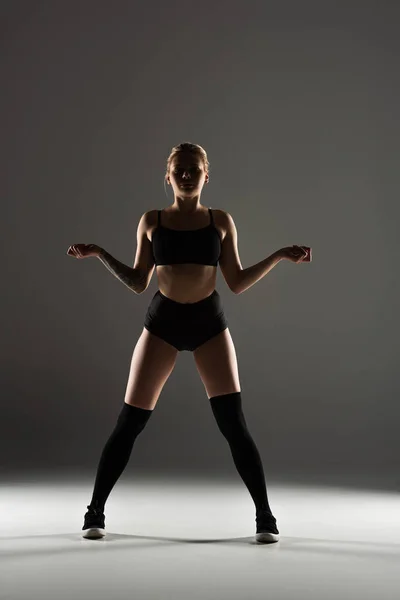 Sexy girl in black outfit  twerking in shadow on grey background — Stock Photo