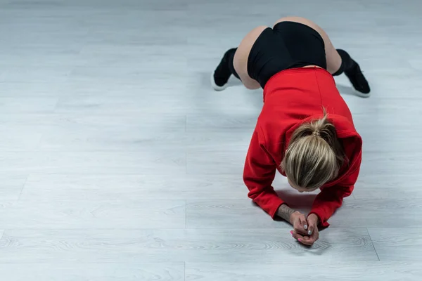 Vista aérea de chica rubia sexy en traje negro y rojo twerking en el estudio - foto de stock