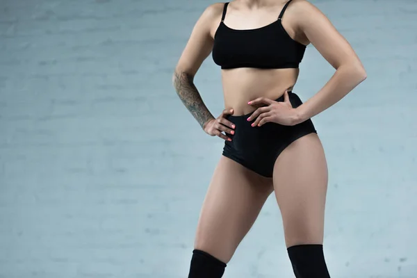 Vue recadrée de tatoué fille sexy en tenue noire posant en studio — Photo de stock