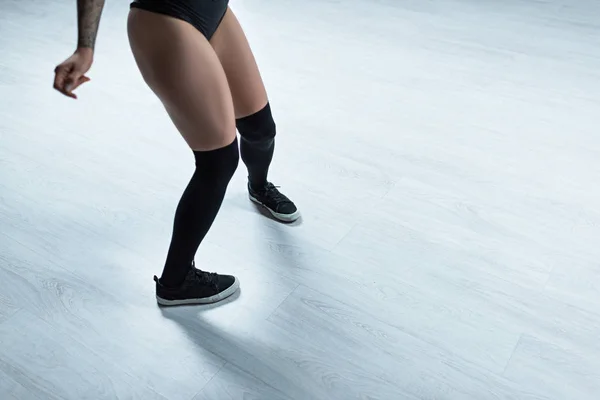 Обрізаний вид татуйованої дівчини в чорному вбранні танцює в студії — стокове фото